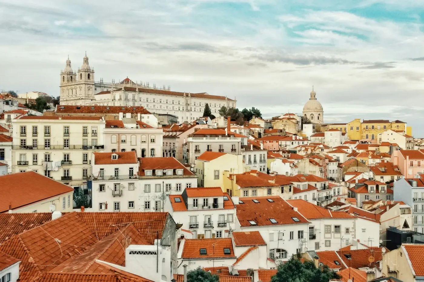 Terracotta rooftops of Alfama in Lisbon, with the São Vicente de Fora monastery and the National Pantheon dome above