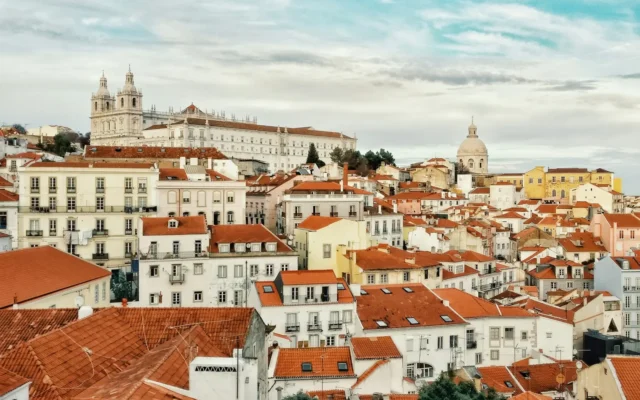Terracotta rooftops of Alfama in Lisbon, with the São Vicente de Fora monastery and the National Pantheon dome above